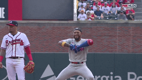 a man in a phillies jersey stands on a baseball field