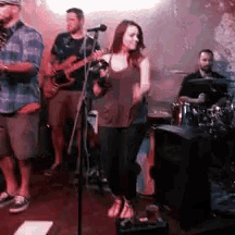 a woman is singing into a microphone while a man plays a guitar