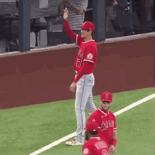 a baseball player is standing on a field giving a high five .