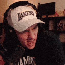 a man wearing headphones and a lakers hat is talking into a microphone