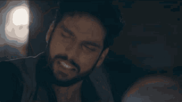 a man with a beard is making a funny face while looking at something .