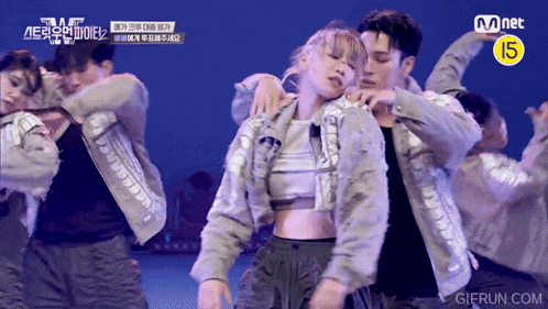 a group of people are dancing in front of a mnet sign