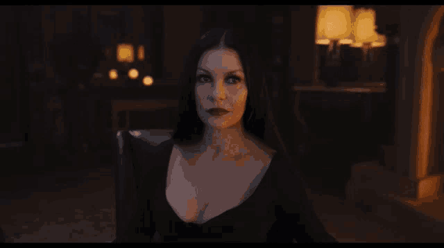 a woman in a black dress with a plunging neckline looks at the camera