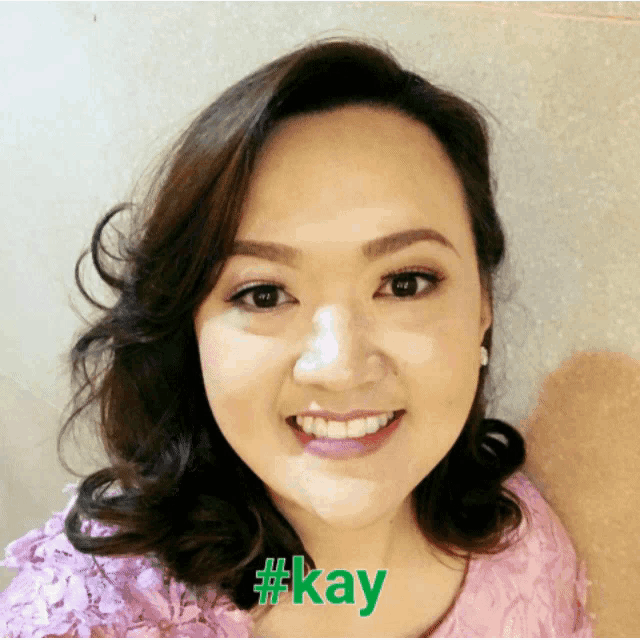 a woman in a pink top is smiling and has the hashtag #kay on her face