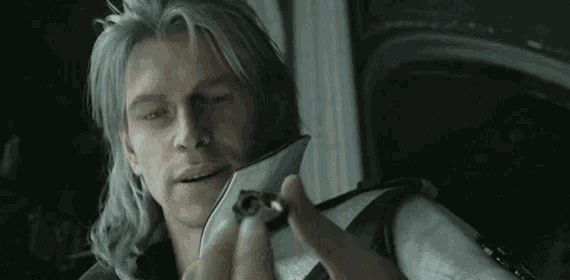 a man with long grey hair is holding a small object in his hand .
