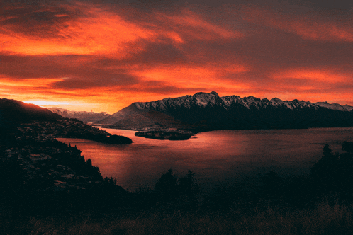 a lake with mountains in the background and a red sky