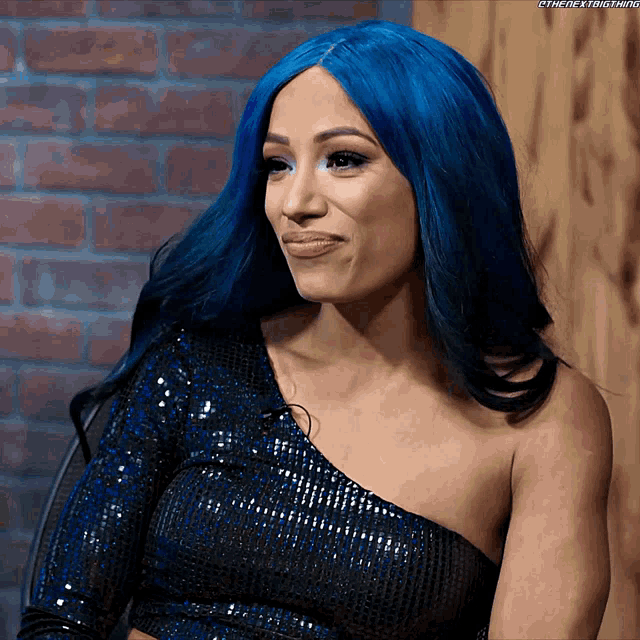 a woman with blue hair is wearing a blue top