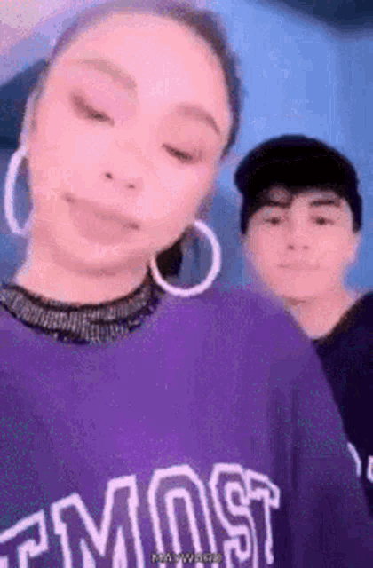 a woman wearing a purple shirt that says most is standing next to a man .