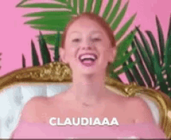 a woman without a shirt is sitting in a chair and laughing with the word claudiaaa written on the bottom .