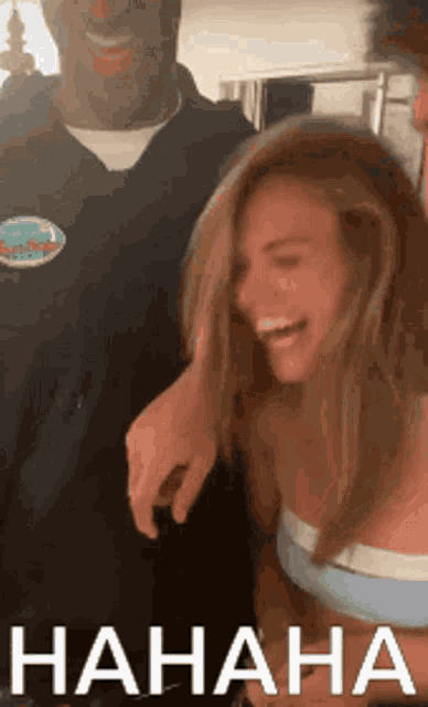 a man and a woman are laughing and the woman is wearing a blue tank top