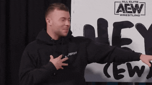 a man is standing in front of a sign that says aew wrestling