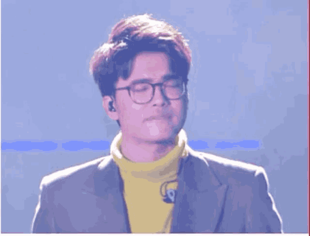 a young man wearing glasses and a yellow turtleneck