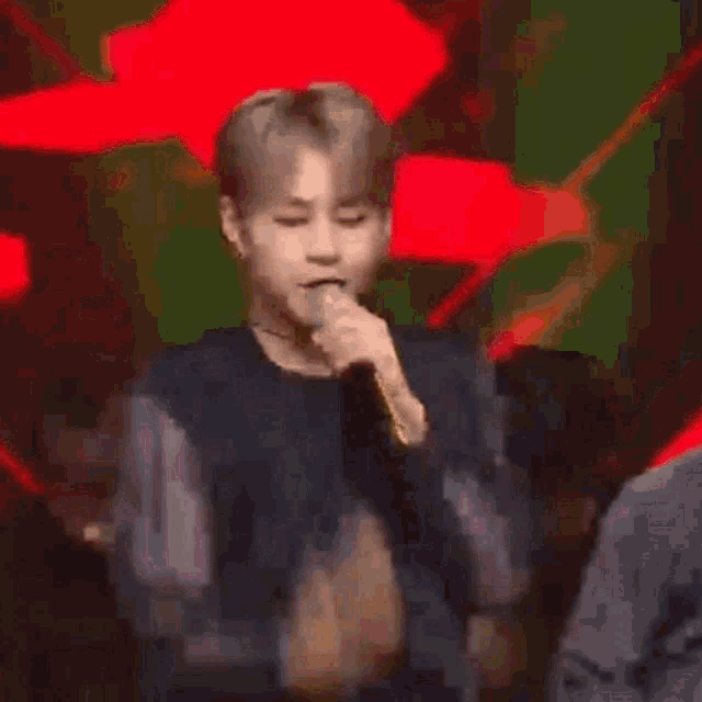 a man is singing into a microphone in front of a red background .