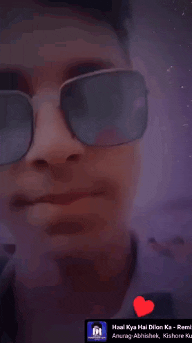 a man wearing sunglasses and a white shirt has a red heart in front of his face