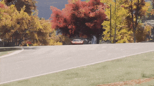 a car is driving down a road with trees on the side