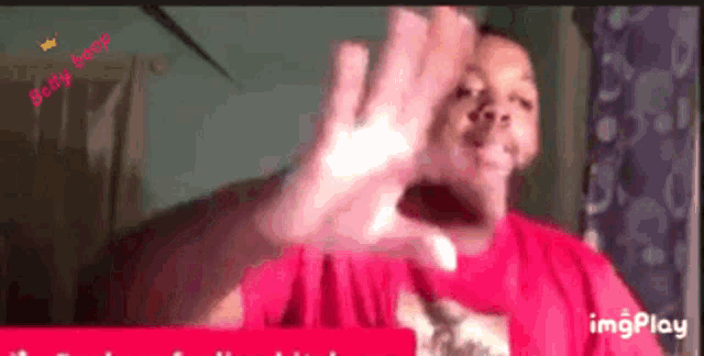 a man in a red shirt is making a funny face with his hands