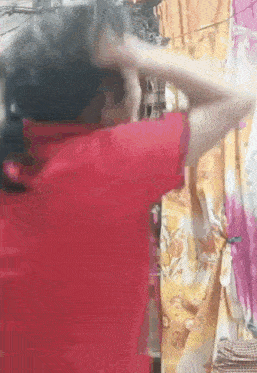 a woman in a red shirt is standing in front of a curtain