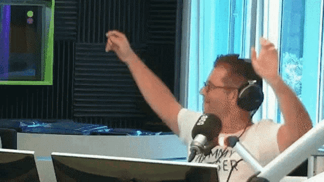 a man wearing headphones and a t-shirt that says " always " on it is dancing in front of a microphone