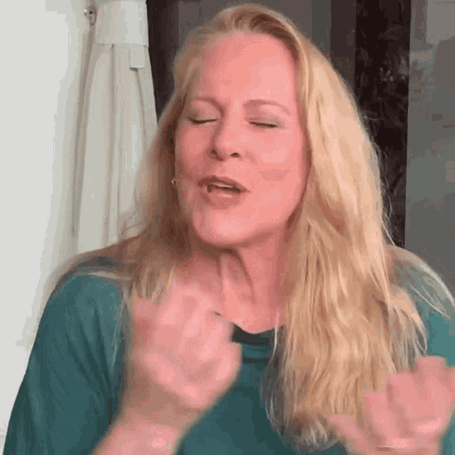 a woman with long blonde hair is making a funny face with her eyes closed .