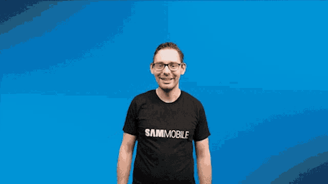 a man wearing glasses and a black shirt that says damnmobile is raising his arms in the air