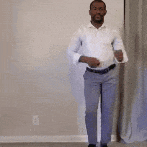 a man in a white shirt and grey pants is standing in a room .