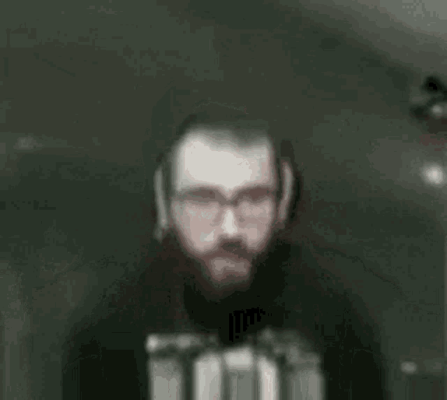 a man with a beard and glasses is holding a gun in his hands .