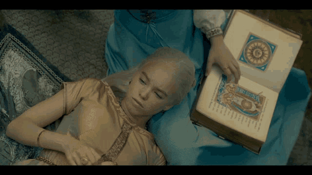 a woman laying on a bed with a book that says ' a ' on the cover