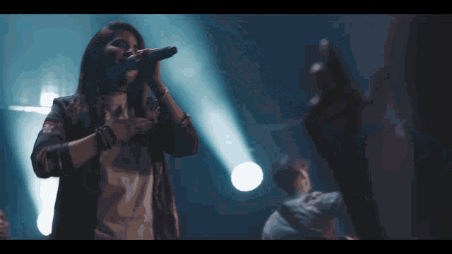 a woman singing into a microphone while a man stands behind her