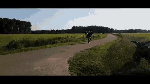 a person is riding a bike down a road in a field