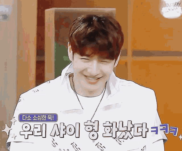 a young man is smiling in front of a sign that says " 우리 사이 "