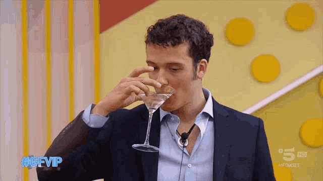 a man in a suit drinks from a martini glass with the gfvip written on the bottom