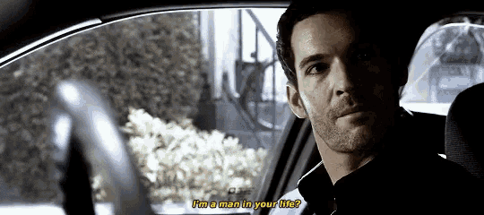a man is sitting in the driver 's seat of a car talking to another man .
