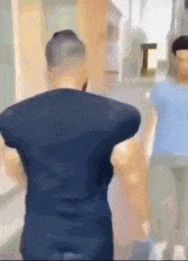 a man in a black shirt is standing in front of a mirror looking at himself .