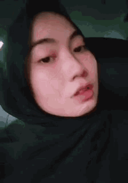 a woman in a black hijab is sitting in a car .