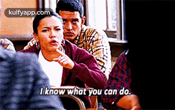 a woman is sitting at a table talking to a man while another man looks on .
