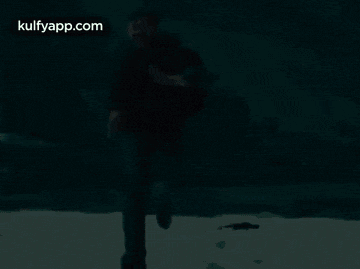 a man is running in the snow while holding a frisbee .