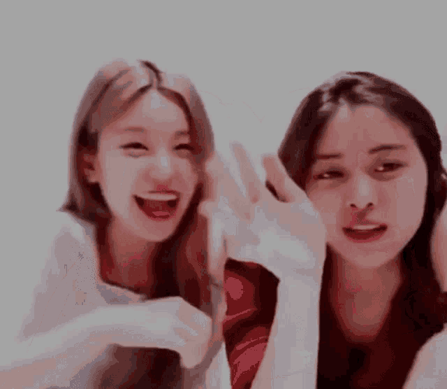 two young women are laughing and making funny faces while sitting next to each other .