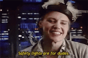 a woman wearing a hat is smiling and saying safety lights are for dudes .