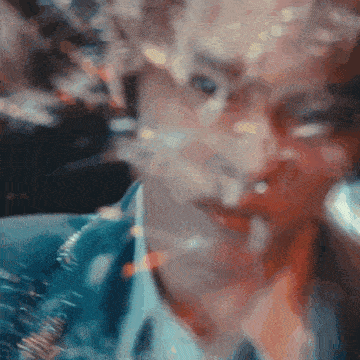 a blurry picture of a man 's face with a blue jacket