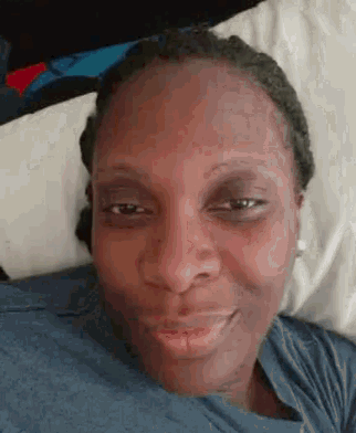 a close up of a woman 's face while laying on a bed .