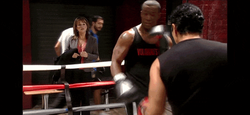 a woman is standing next to a man in a boxing ring with a sign that says notice in the background .