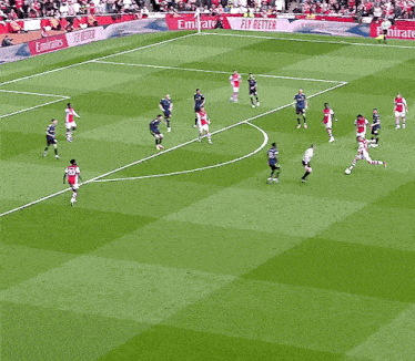 a soccer game is being played on a field with emirates advertisements on the sidelines