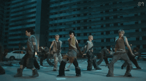 a group of people are dancing in front of a building with the letter s on the bottom