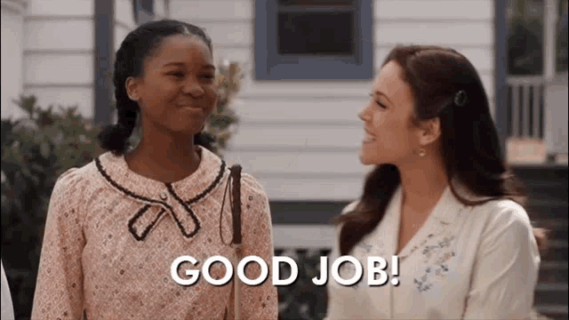 two women are standing next to each other in front of a house and the words `` good job '' are written on the screen .