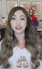 a woman with long brown hair is wearing a white shirt with a bunny on it .