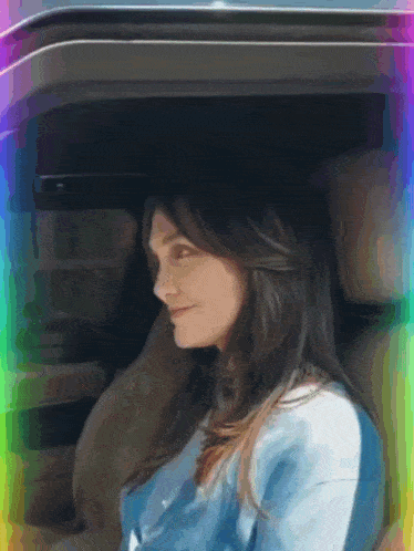 a woman is sitting in the back seat of a car with a rainbow in the background