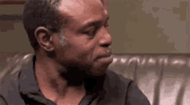 a man is sitting on a couch with his mouth open and making a funny face .