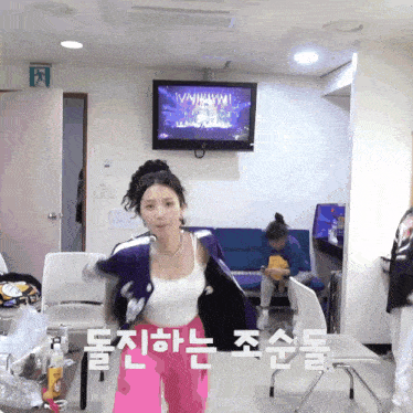 a woman stands in front of a flat screen tv with a foreign language on the screen