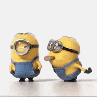 two minions wearing goggles and overalls are standing next to each other on a table .