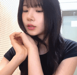 a woman in a black shirt has her hands on her chin